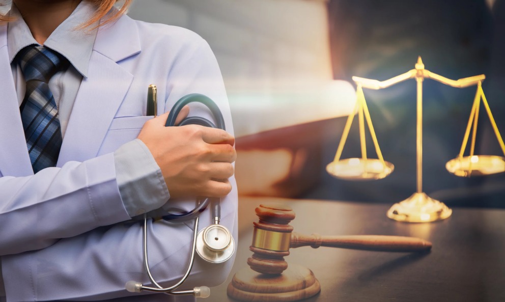 Médico utilizando jaleco e estetoscópio na mão, com símbolos da justiça ao seu lado.